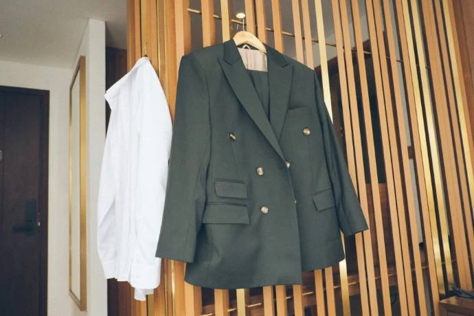 A dark green suit jacket and white shirt hanging.